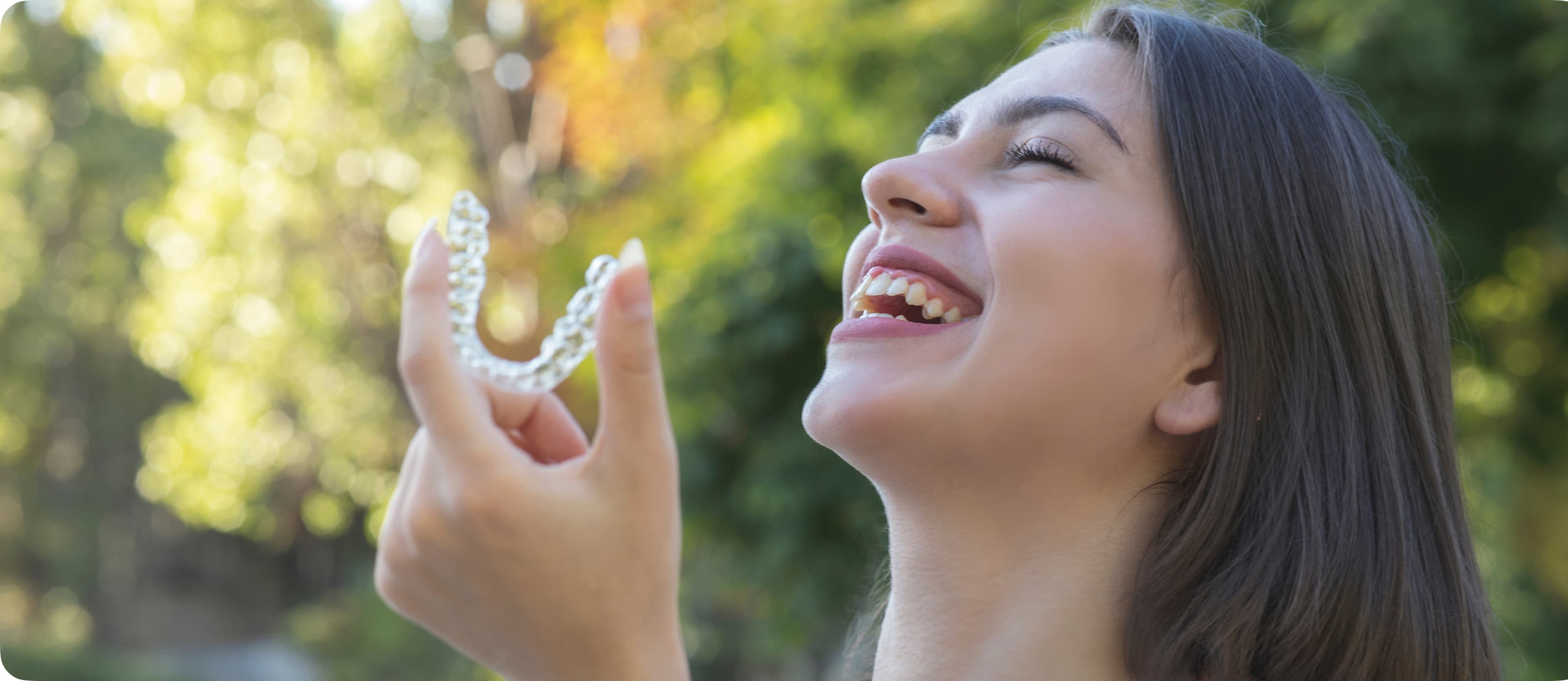 Smiling patient holding Invisalign aligners at Taverham Dental